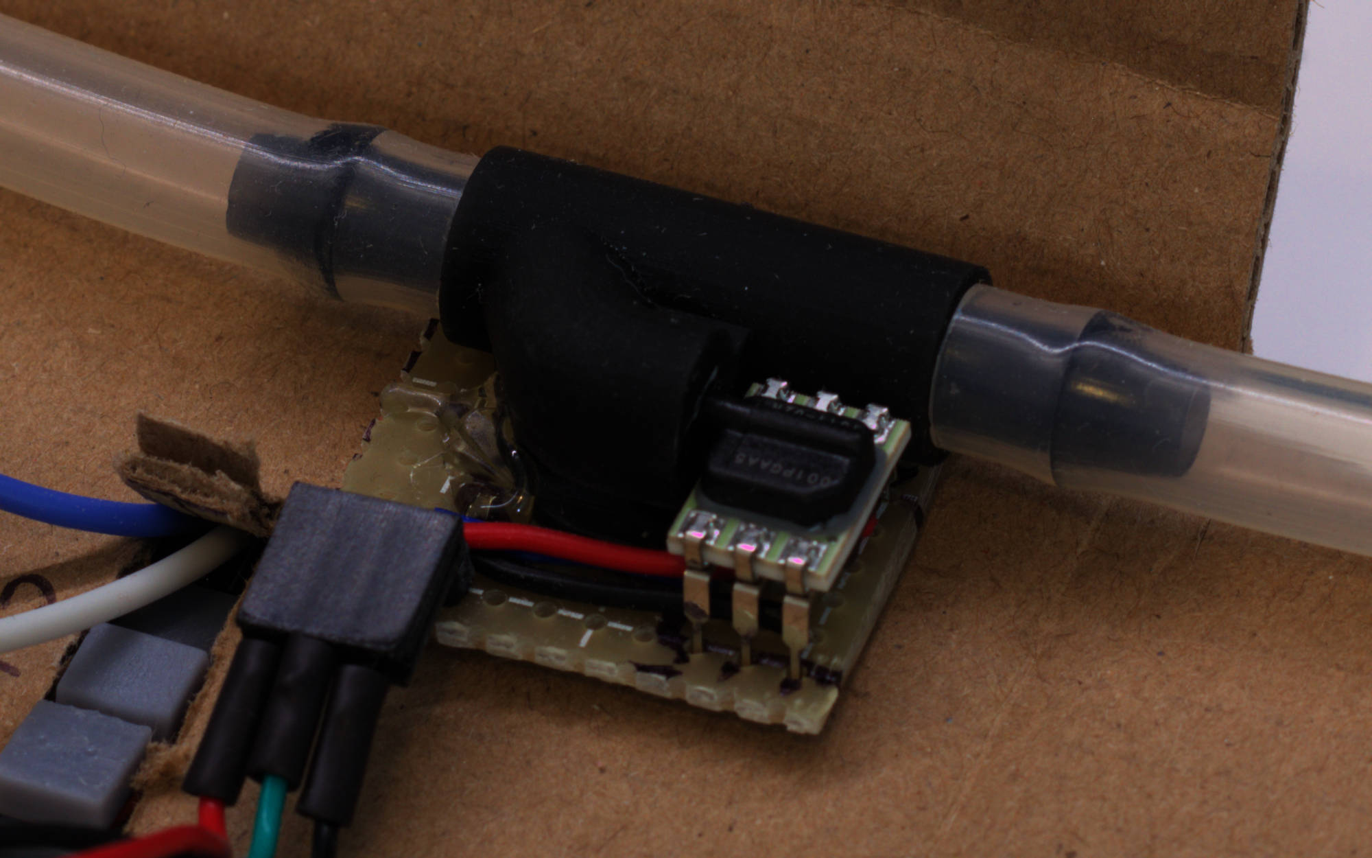 Close-up of Y-splitter with a large silicone tube connected to 2 of the ends. The third smaller end goes to a pressure sensor which is shaped like a 6-pin DIP package with a plastic box on top of it